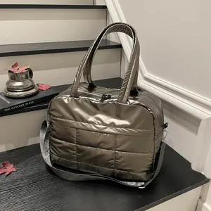 Metallic quilted tote bag with dual handles and adjustable shoulder strap on table