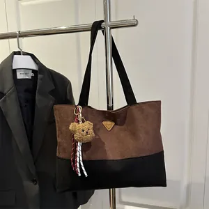 Large two-tone tote bag in dark brown and black suede with a gold metal triangle logo
