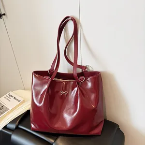 Deep red glossy tote bag with a silver metal bow accent and comfortable double straps