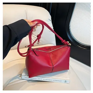 Retro red faux leather shoulder bag with lychee texture on a white armchair