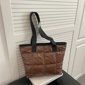 Borsa tote trapuntata marrone scuro con ampi manici neri su uno sfondo minimalista