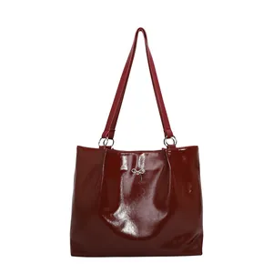Deep red patent leather tote bag with silver metal bow detail and sleek polished finish