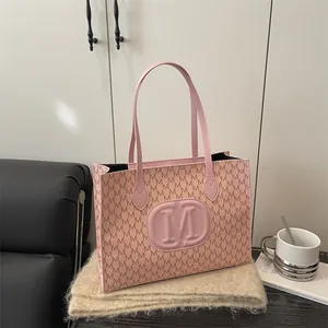 Pink tote bag with all-over M monogram print and embossed logo in a cozy home setting