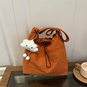 Large orange nylon drawstring tote bag with plush cloud charm for casual daily use