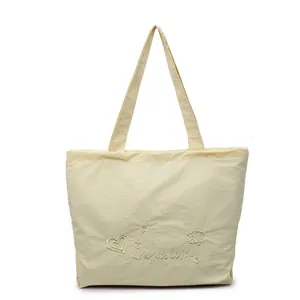 Bolso tote beige crema con bordado dulce y textura plisada sobre fondo blanco