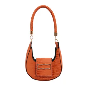 Orange semi-circle baguette bag with crocodile texture and gold hardware on white background