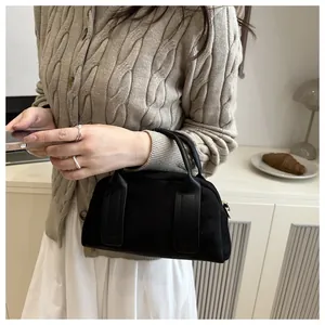 Detailed close-up of a black suede Boston bag featuring cylindrical handles and textured finish