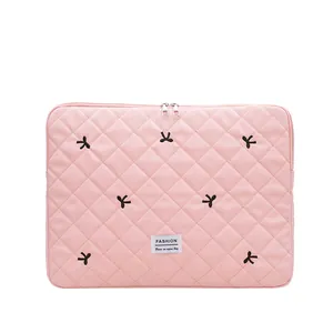 Pink quilted laptop sleeve with black bows and fashion label in minimalist design