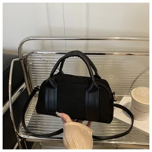 Detail of minimalist black faux suede boston bag showing premium texture and gold hardware