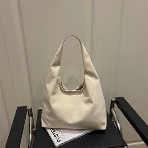 Minimalist cream white hobo tote bag in matte leather on a stylish chair scene