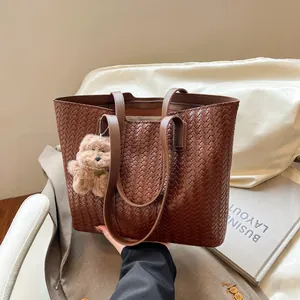 Brown woven tote bag with shoulder straps and cute plush bear charm for women