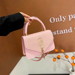 Pink faux crocodile embossed flap bag with gold tassel logo and detachable strap