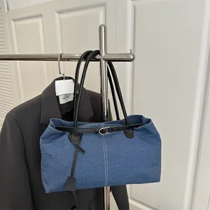 Borsa tote minimalista in denim blu con cinturini in pelle nera e fibbie dorate