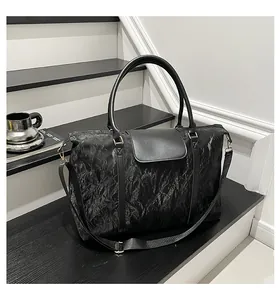 Dettaglio della borsa nera capiente con trama plissettata e accessori in metallo dorato