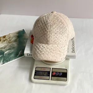 Détail d'une casquette en velours rose avec strass sur une balance pesant 121g