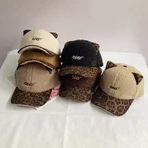 Pile of plush cat ear baseball caps in various colors with leopard print brims and embroidery