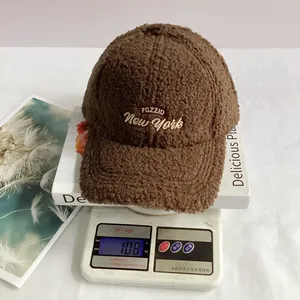 Detailed view of brown teddy fleece baseball cap showing 108g weight on digital scale