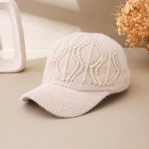 Close-up of cream knit baseball cap featuring wave-shaped rhinestone accents and soft texture