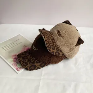 Detail of plush cat ear baseball caps featuring leopard print brims and meow embroidery