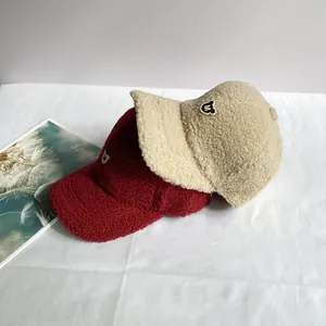 Detail von Fleece-Baseballcaps in Beige und Burgund mit gesticktem M-Logo-Aufnäher