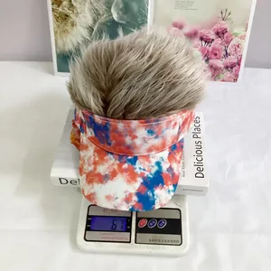 Detailed view of tie-dye visor hat with brown synthetic hair on a digital scale weighing 67g