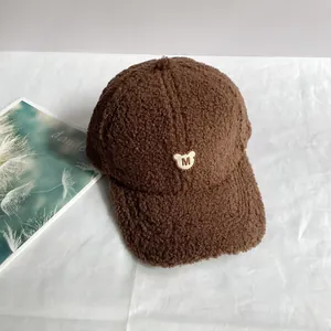 Detailansicht der dunkelbraunen Plüsch-Basecap mit Teddybär-Stickerei und dem M-Logo