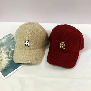 Detail of R logo embroidery on warm beige and red sherpa fleece baseball caps