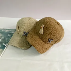 Détail de casquettes en laine d'agneau beige et marron avec petit lapin et nœud papillon