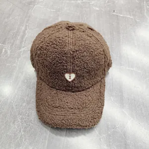 Dettaglio del cappello da baseball marrone in lana di agnello con ricamo a cuore
