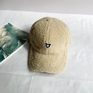 Nahaufnahme der beigen Fleece-Baseballkappe mit schwarzem Bärenaufnäher und M-Stickerei