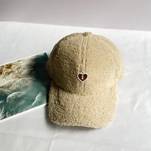 Dettaglio del cappellino beige in lana di agnello con ricamo a cuore e pile morbido