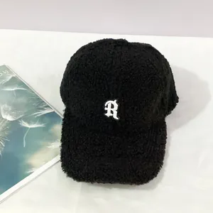 Close-up of black fuzzy lamb wool baseball cap featuring white embroidered R letter
