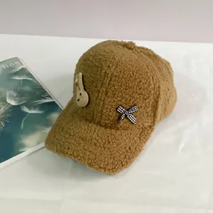 Détail de la casquette de baseball marron en polaire peluche avec lapin et nœud à carreaux
