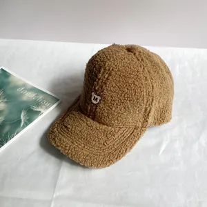 Detail einer braunen Teddy-Fleece-Baseballkappe mit weißer M-Bären-Stickerei