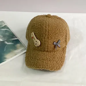 Détail de la casquette marron en polaire avec écusson lapin et nœud à carreaux chic