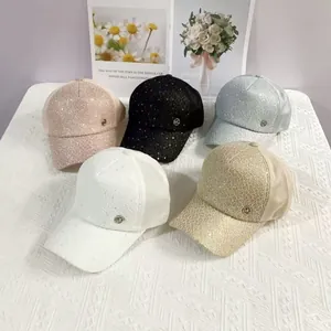 Flat lay of lace baseball caps with sequins and metallic MC logo in five assorted colors