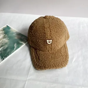 Detailansicht der braunen Fleece-Basecap mit weißem Bären- und M-Stickmotiv