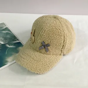 Détail de la casquette beige en laine d'agneau avec patch lapin et nœud à carreaux