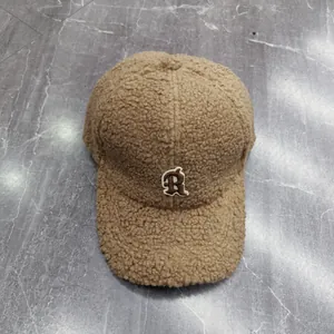 Detail of brown teddy fleece baseball cap featuring a white R letter embroidery
