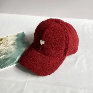 Dettaglio del cappellino da baseball in lana di agnello rosso scuro con ricamo a cuore e I