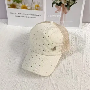 Detail of mesh baseball cap with gold sequins and a metallic butterfly accessory