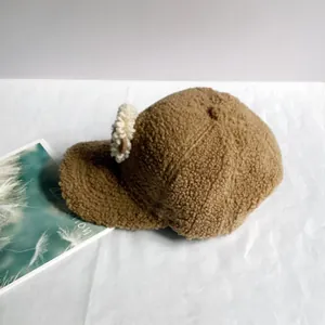 Détail d'une casquette de baseball marron en polaire avec une fleur blanche