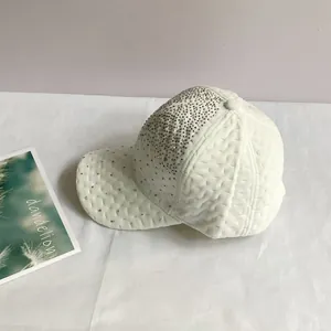 Gros plan d'une casquette de baseball blanche matelassée avec des strass argentés brillants
