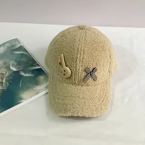 Détail de la casquette en polaire beige avec petit lapin en bois et nœud à carreaux