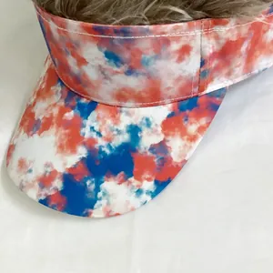 Detail of red and blue tie-dye sun visor with realistic brown synthetic hair wig on top