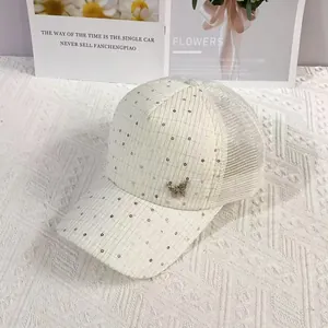 Detail of cream mesh baseball cap with silver sequins and decorative metal butterfly