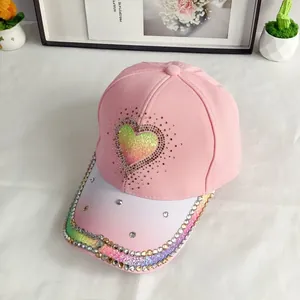 Detail of gradient baseball cap featuring colorful rhinestone heart and sparkling brim edge