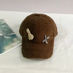 Détail de la casquette d'hiver en peluche avec écusson lapin et nœud à carreaux