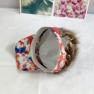 Detail of a tie-dye baseball cap featuring integrated brown synthetic hair and adjustable strap