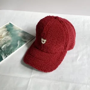 Detailaufnahme der roten Teddy-Fleece-Baseballkappe mit besticktem Bären-M-Aufnäher